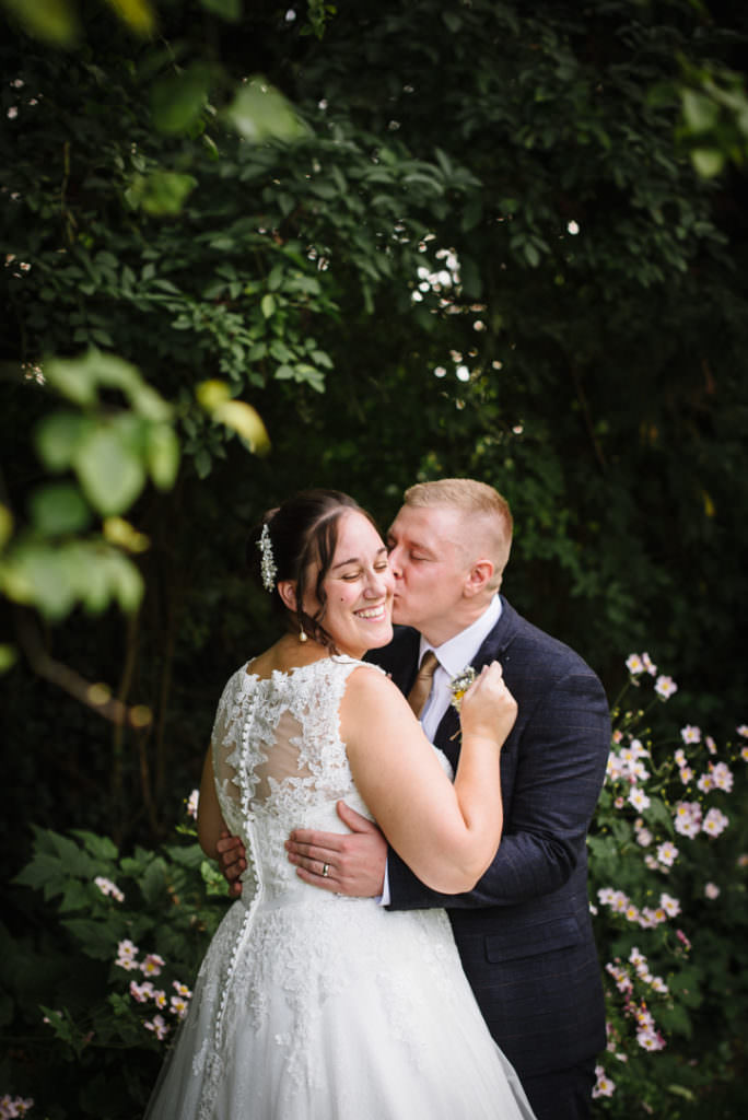 surrounded by flowers the sheene mill bride and groom kiss with hertfordshire wedding photographer