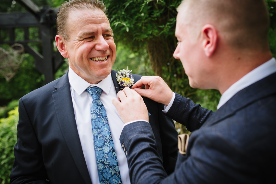 groom straightens his dads button hole