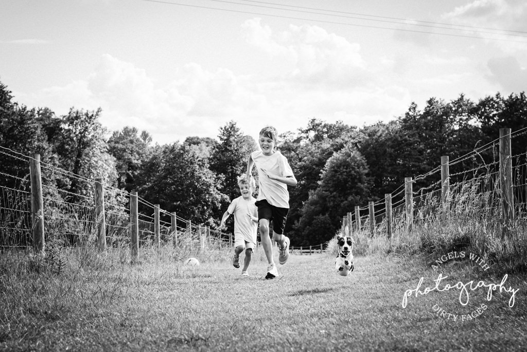 boys and their dog run together on family photo shoot