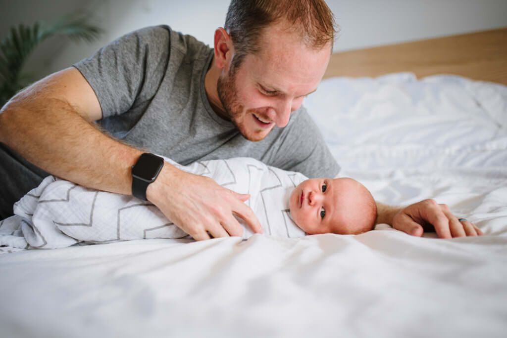 dad and newborn cuddle on the bed