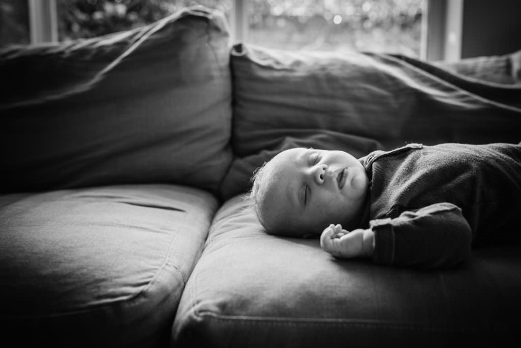 Hertfordshire newborn boy lies on the sofa for his photography session