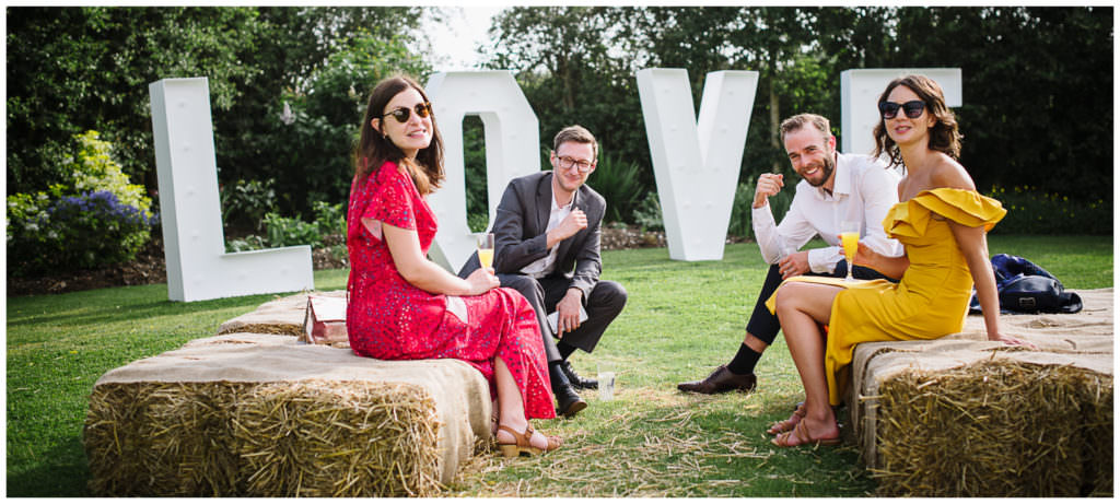 guests gather on hay bales at intimate wedding at rowley barn in hertfordshire