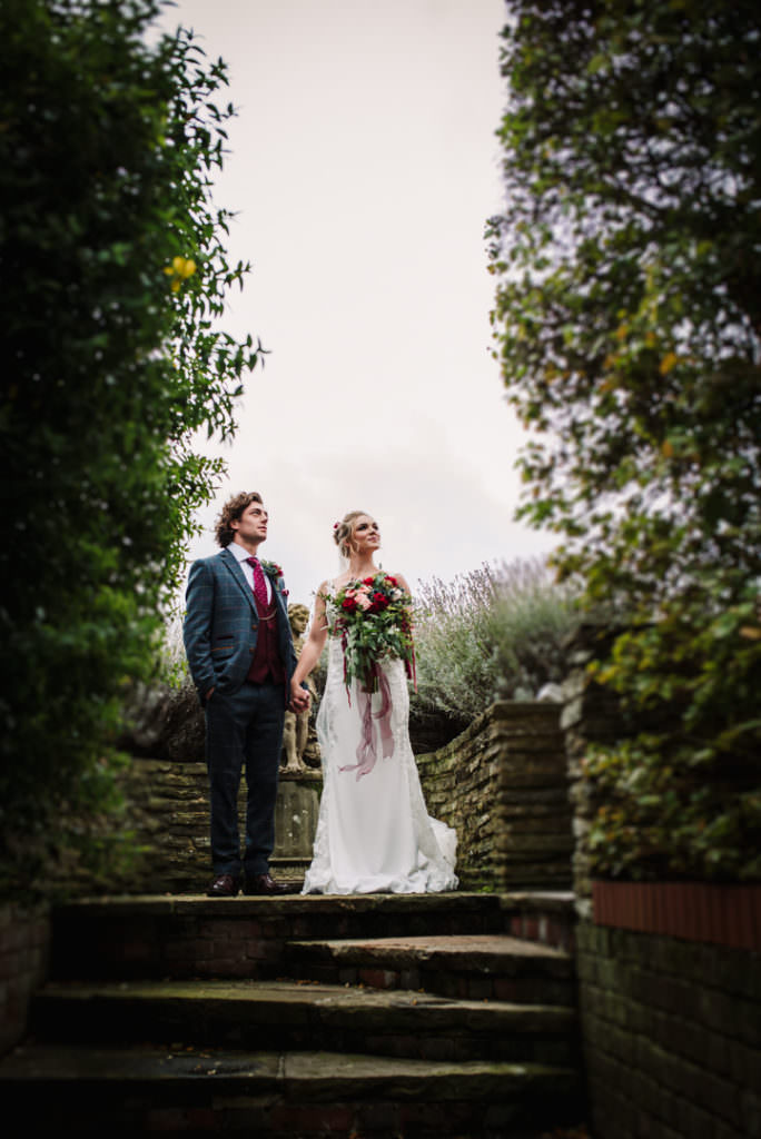 bride and groom look into the distance in the gardens at brocket hall wedding venue