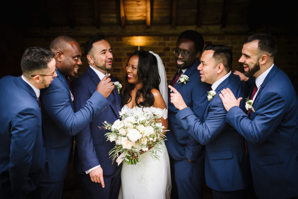 bride and groomsmen joke during their wedding group photos