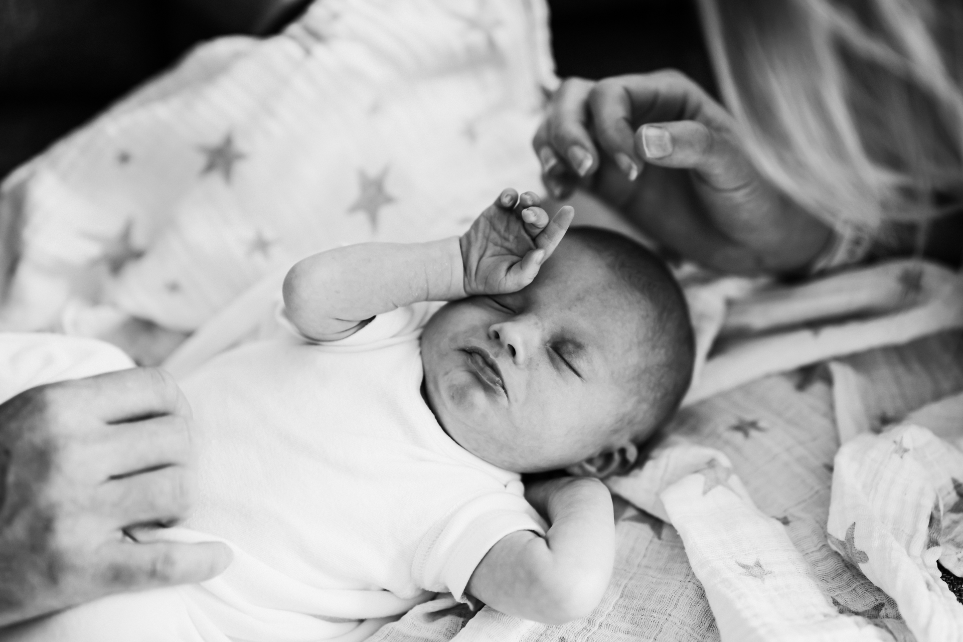 Sleepy newborn starts to wake as photographer captures the natural moment