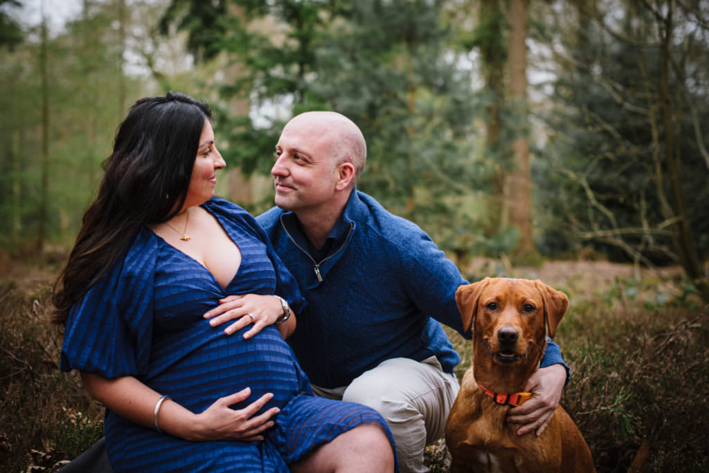 36 week pregnant mother, her partner and beloved family dog pose for Hertfordshire maternity photographer in woodland setting