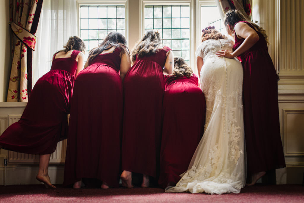 london Wedding photographer captures the bridal party looking out the window in anticipation