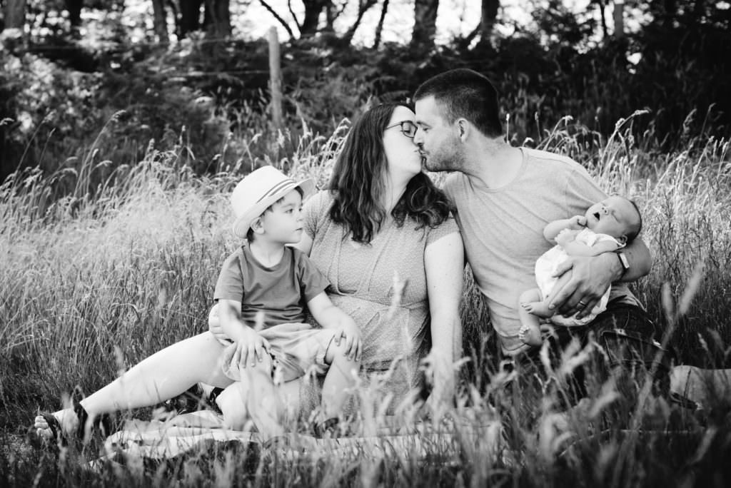 parents kiss as their child looks on during their family photography session