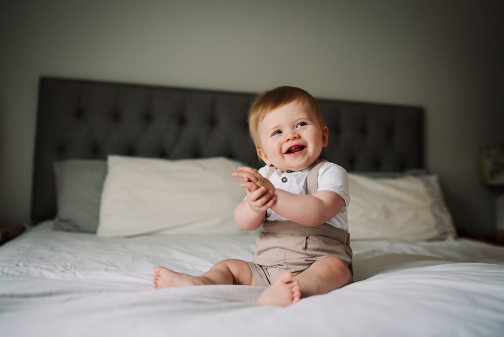 Laughing baby boy photographed on his parents bed in Hertfordshire