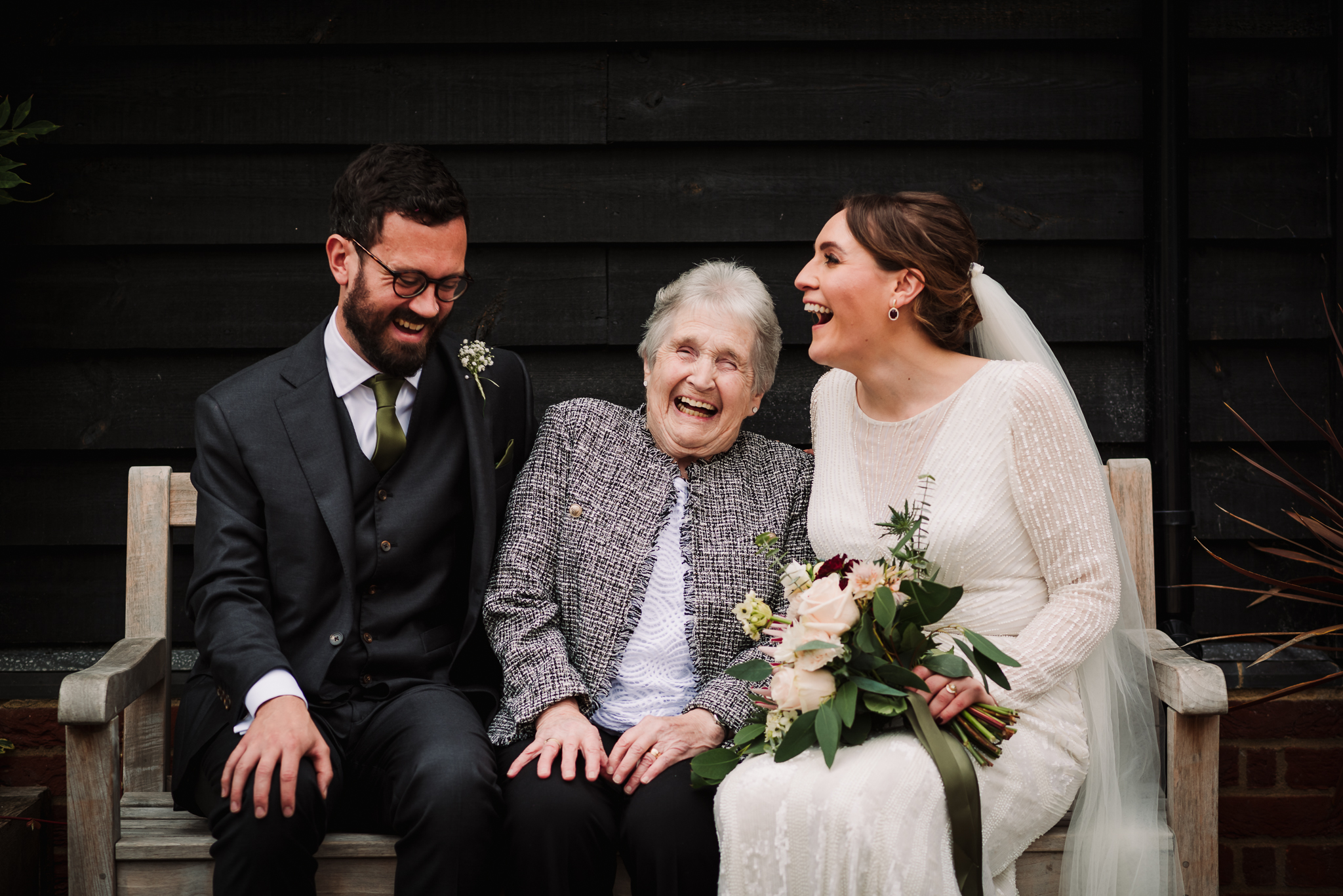 bride and groom laugh with gran at the farmhouse at redcoats wedding reception