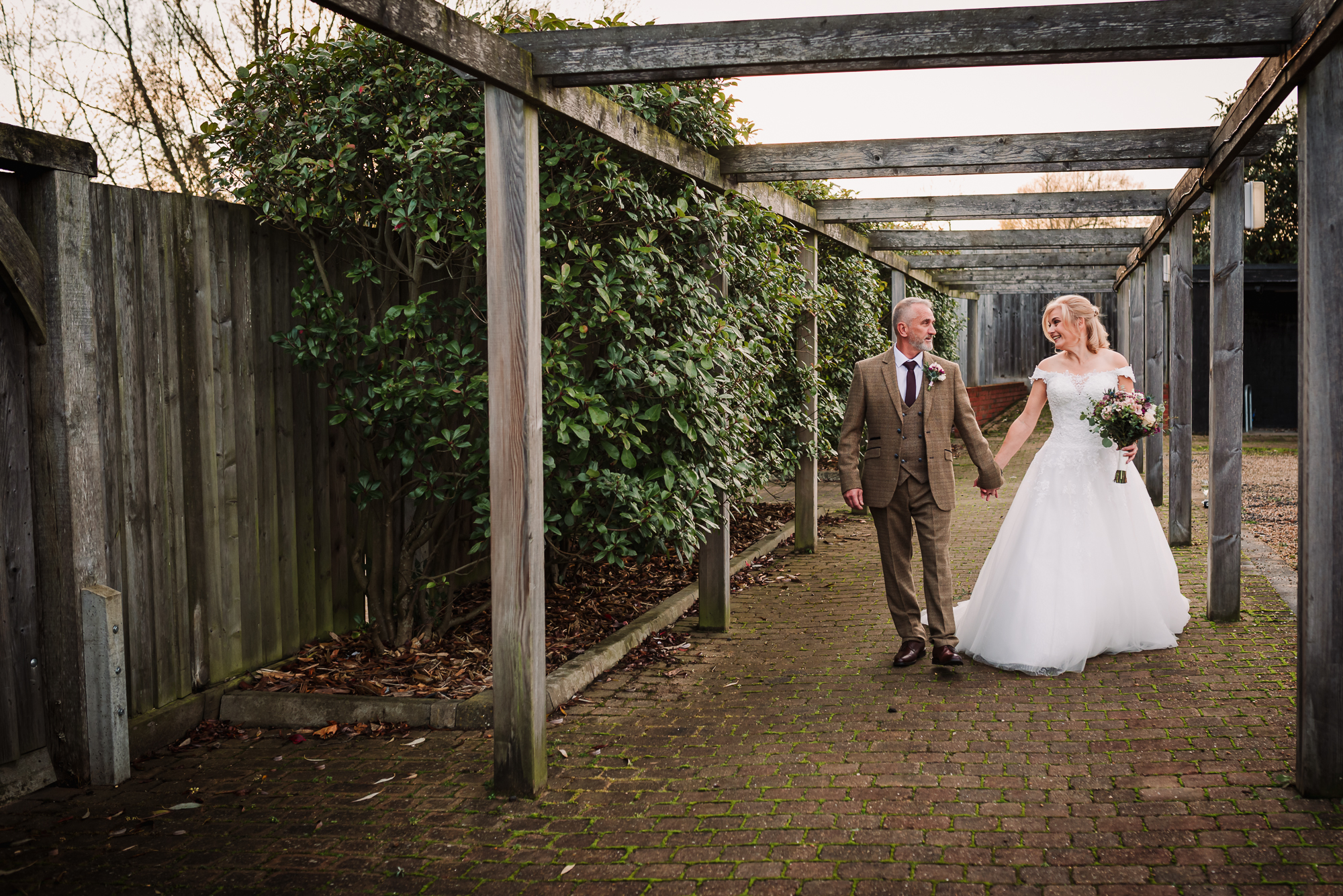 bride and groom walk hand in hand through the gardens of tewin bury farm hotel