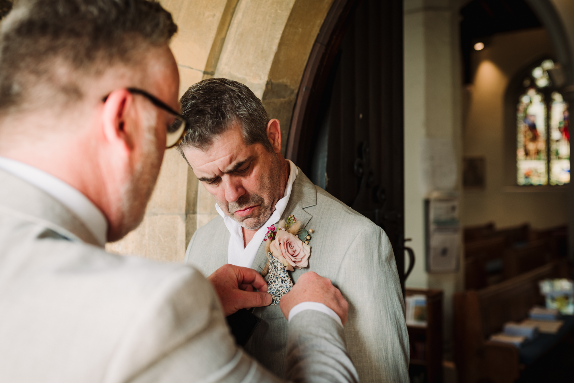 Groom adjusts his button hole for his pub wedding photographer