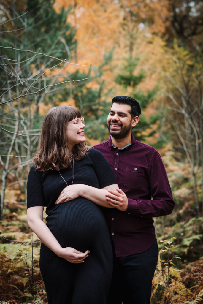relaxed and laughing couple cradle their baby bump