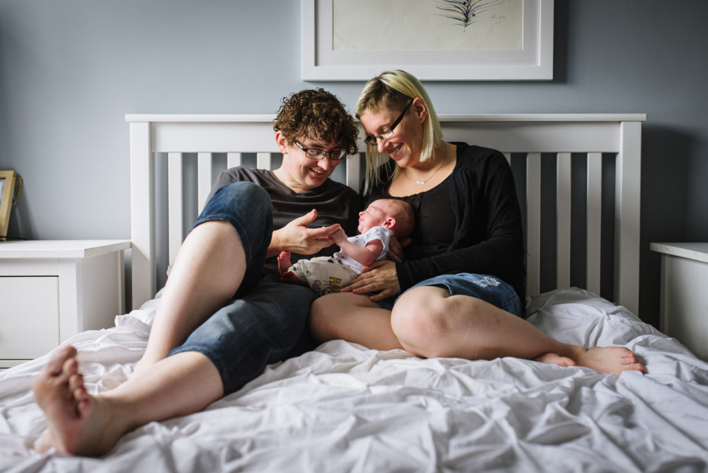 Proud parents cradle their newborn baby boy in their Hertfordshire home