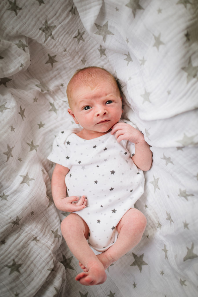 Brand new baby looks straight into the camera during his newborn photography session