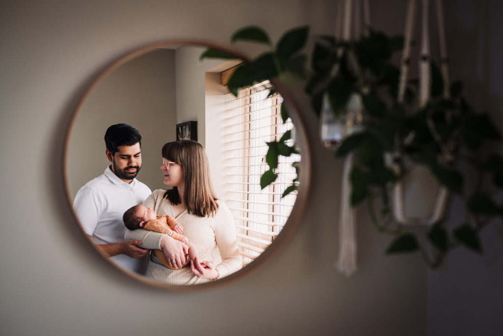 mirror image of newborn and her parents at home