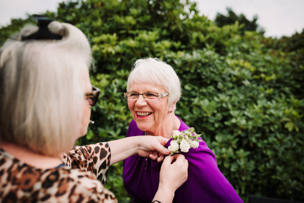 mother of the groom gets help with her button hole at hertfordshire same sex wedding