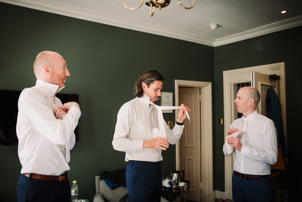 groomsmen try and tie their ties at Wadhurst Castle Wedding 