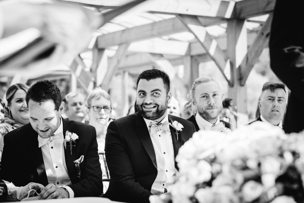 best man pulls faces at the photographer during the gaynes park wedding ceremony
