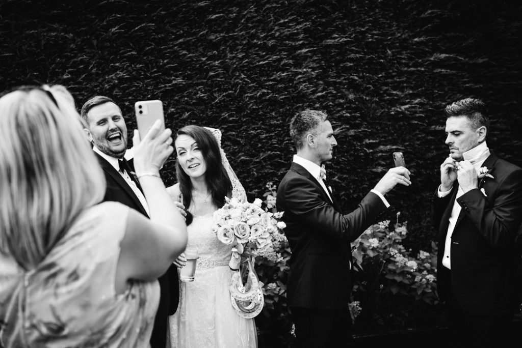 photographer captures guests on their mobile phones after the gaynes park wedding ceremony