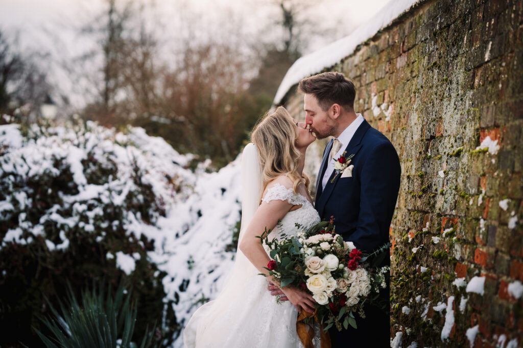 a snowy kiss between bride and groom captured by offley place wedding photographer