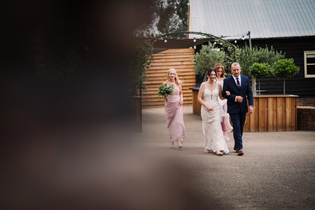 brides walks to meet her husband to be at their milling barn wedding