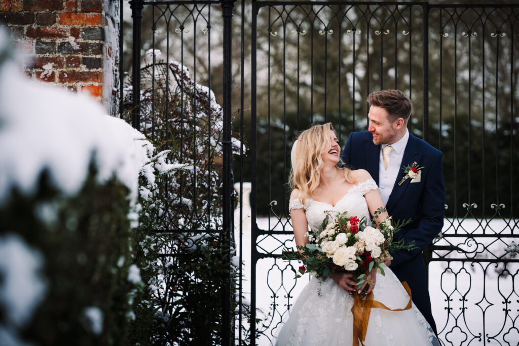 bride and groom laugh in the snow as their photo is taken at offley place wedding