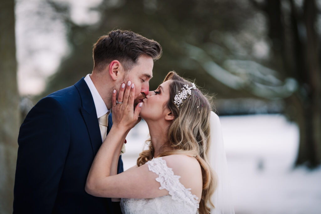 bride and groom have their first kiss in the snow at their offley place wedding 