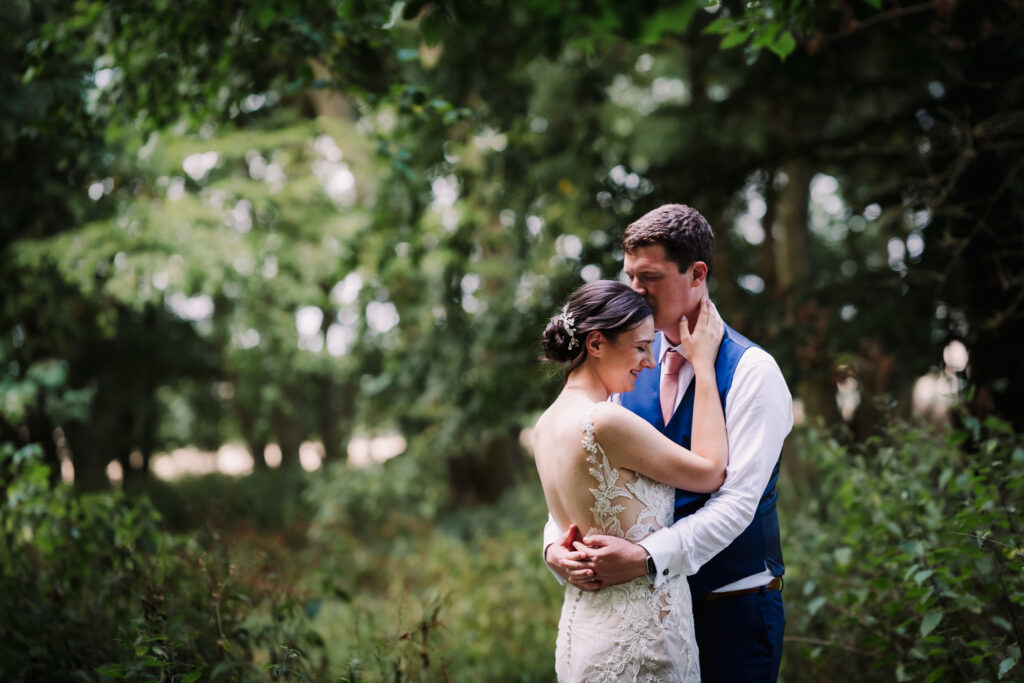bride and groom are photographed in the woodland at milling barn wedding