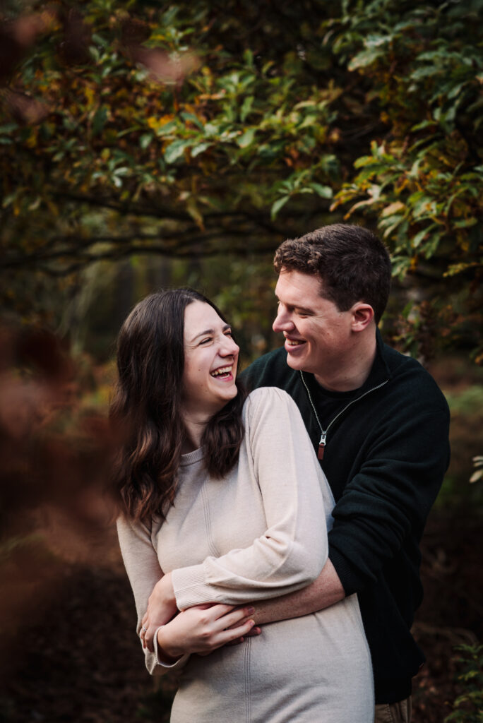 young couple share a joke amongst autumn woodland setting in Hertfordshire