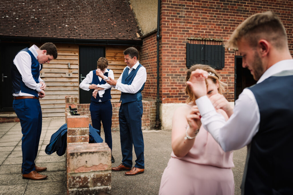 Groomsmen get ready by doing their cufflinks up before the Milling Barn wedding