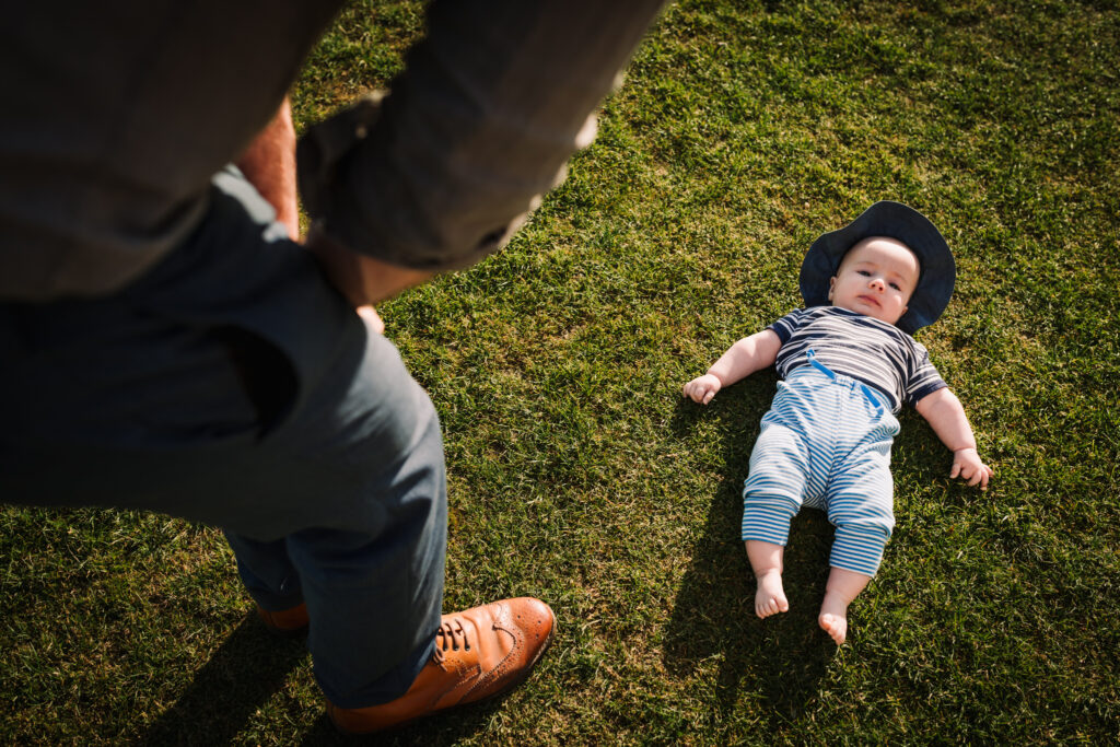 Baby lies on the grass at Gosfield Hall wedding