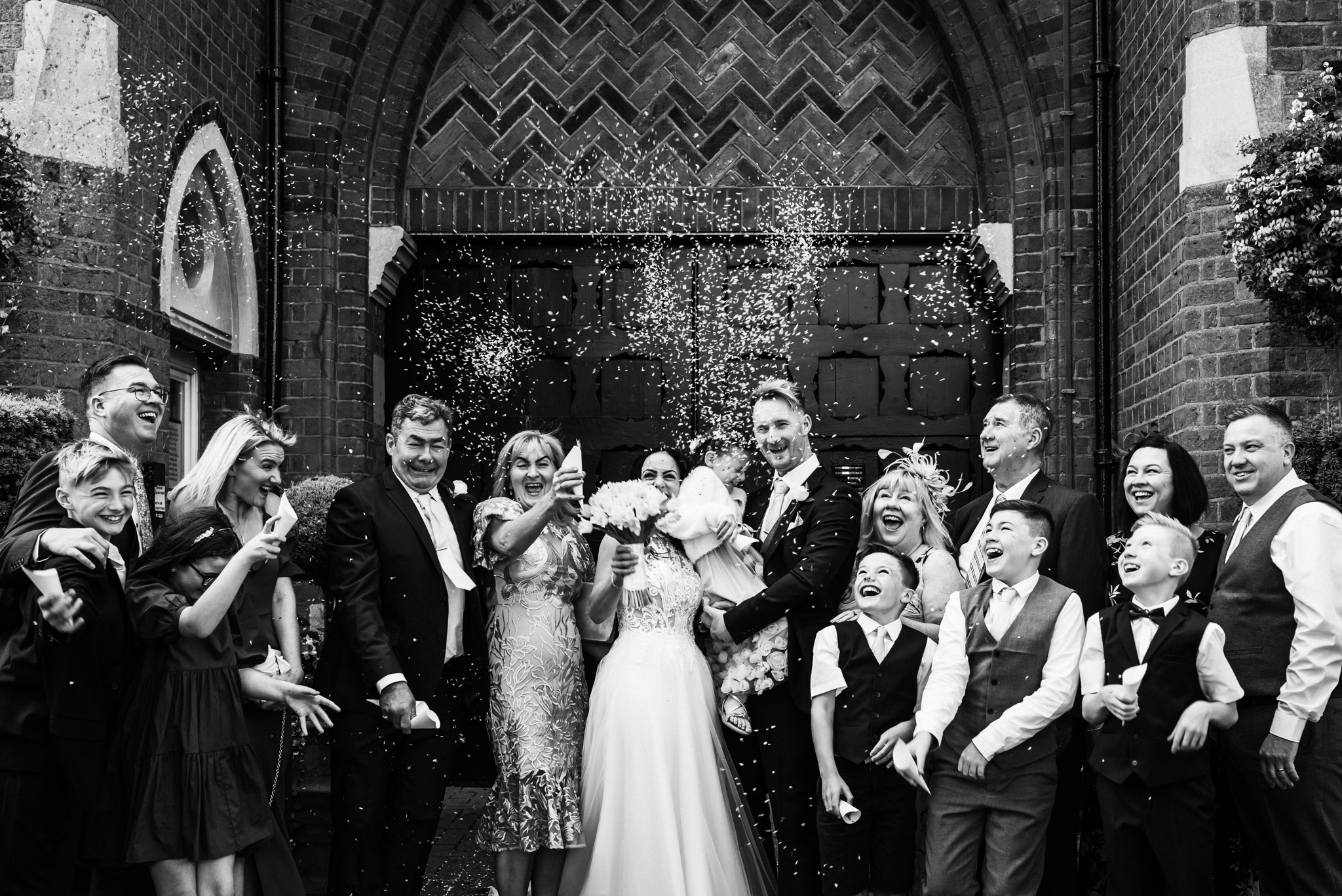 Wedding party celebrate by throwing lots of confetti after Hertfordshire wedding service
