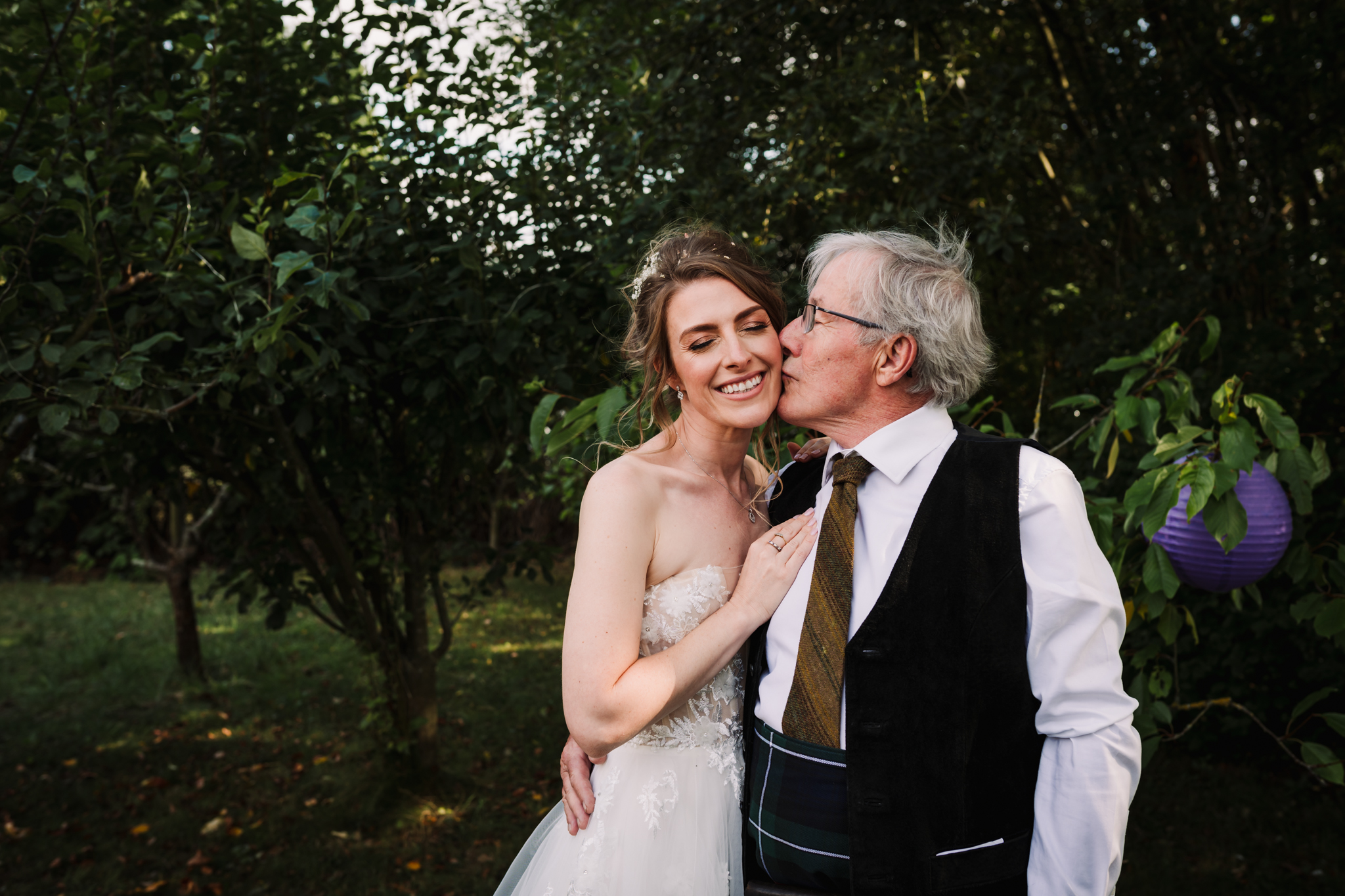 father of the bride kisses her during garden party reception