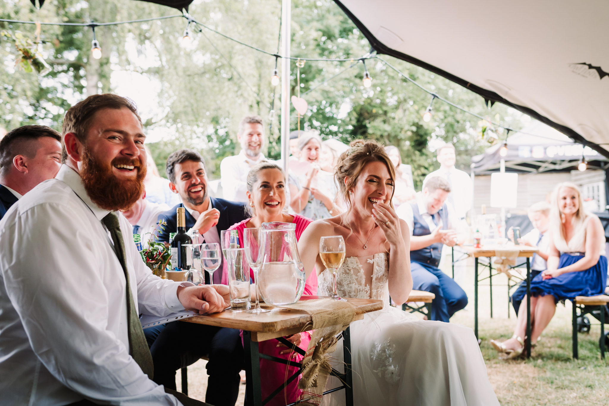 Hertfordshire Garden Party wedding Photographer captures guests laughing at the speeches