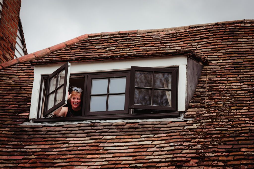 mother of the bride waves from an upstairs window at sheene mill