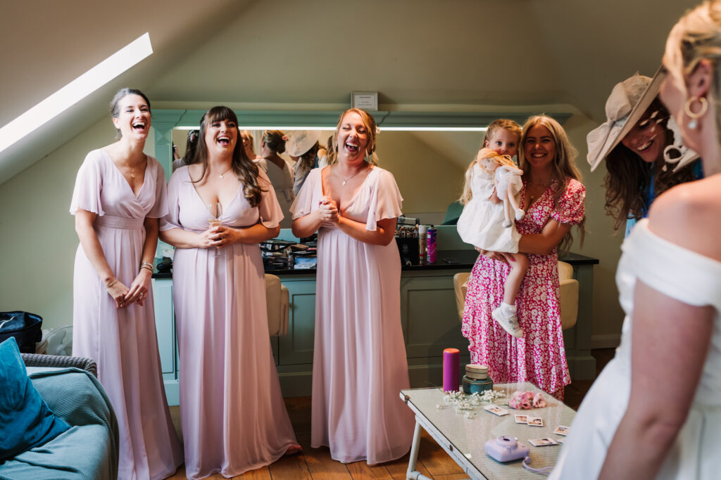 bridesmaids laugh together during wedding preparation