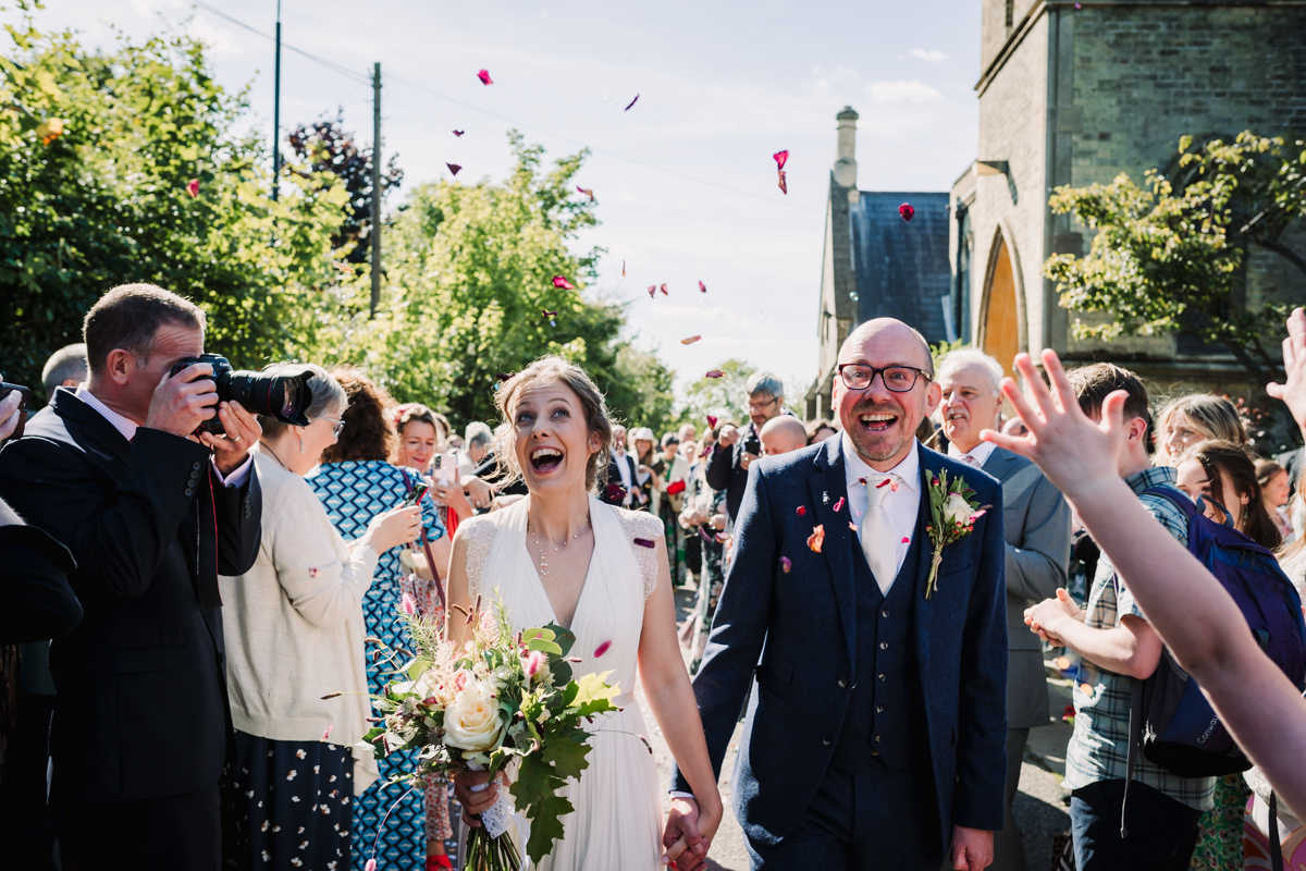 Bride and groom enjoy their confetti outside the church after their wedding ceremony