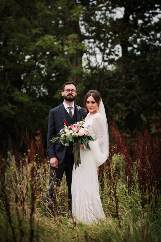 Bride and groom stand amongst the countryside near The Barn at Redcoats
