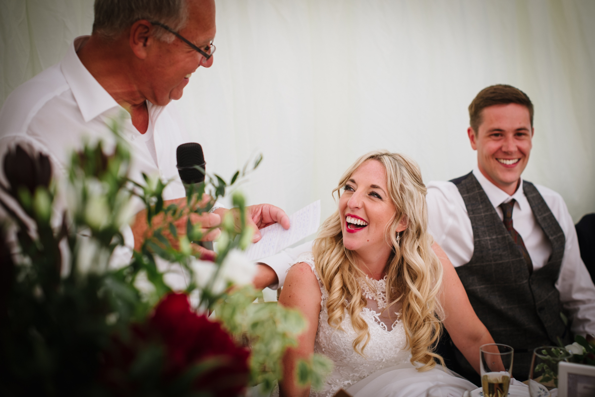 Bride laughs at her dads speech during Rowley Barn wedding reception