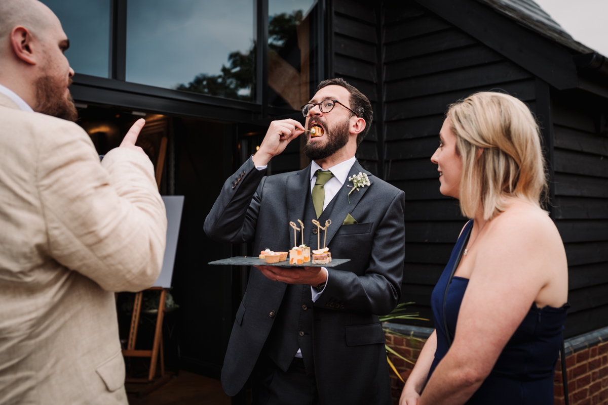 Groom enjoys a canape during his Redcoats Farm wedding reception.jpg