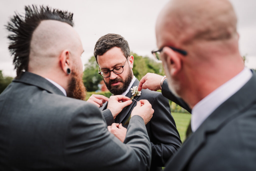 Groom has help attaching his button hole at redcoats Farm.jpg