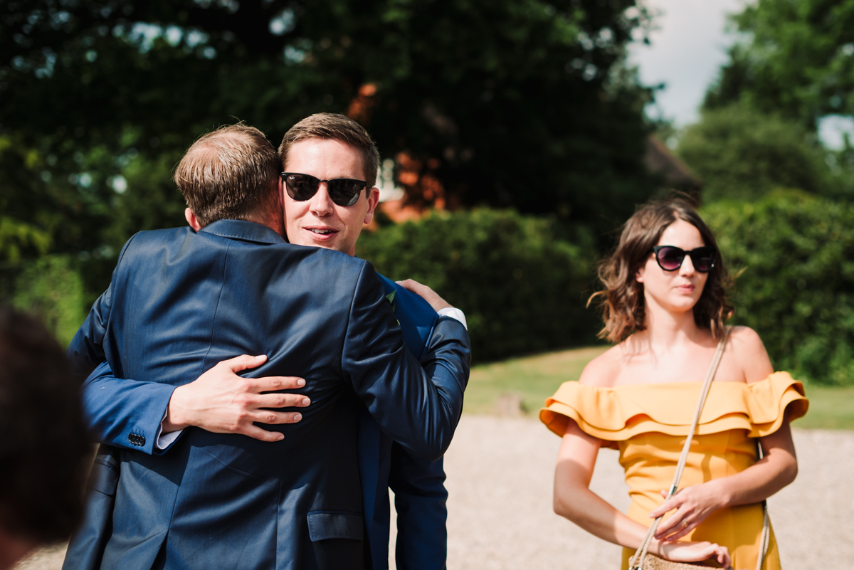 Groom hugs a wedding guest at reception in Hertfordshire
