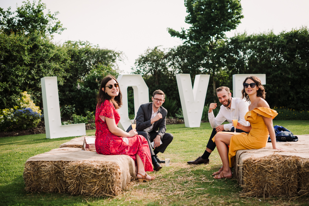 Rowley Barn wedding guests sit on hay bales durinf reception