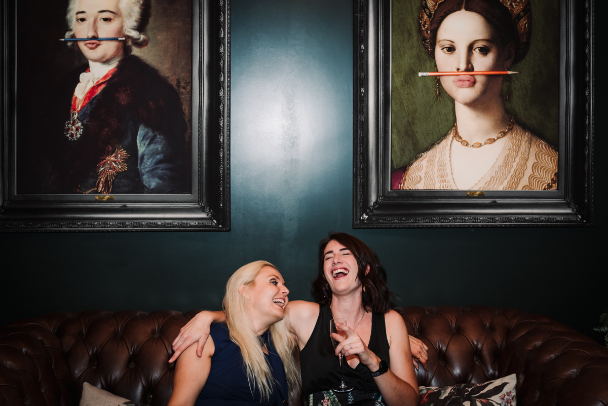 Two drunk guests laugh together under the infamous pictures at Redcoats.