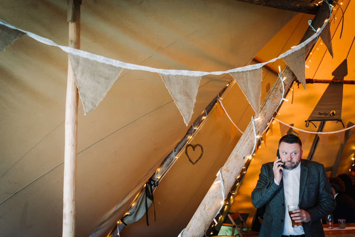 Wedding guest takes a sneaky phone call in the marquee at Rowley Barn