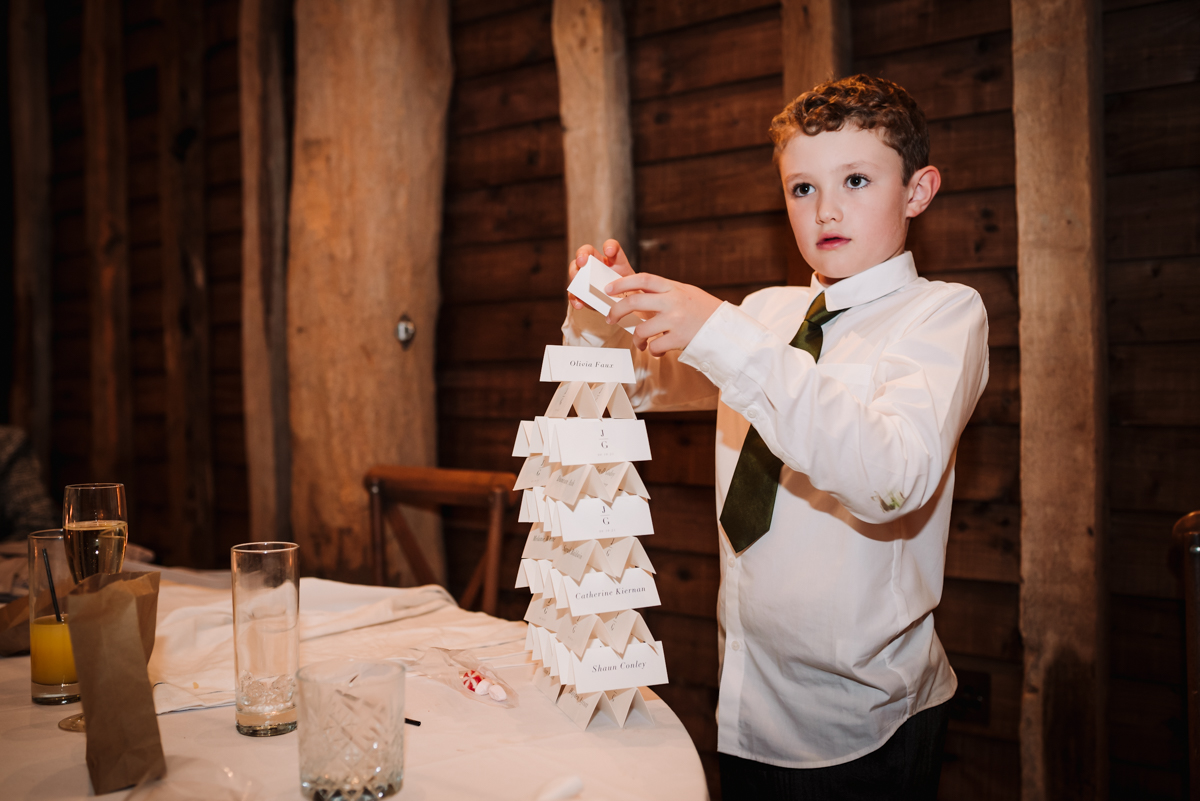 Young wedding guests builds a tower from the name place cards during the wedding reception at Redcoats Farm