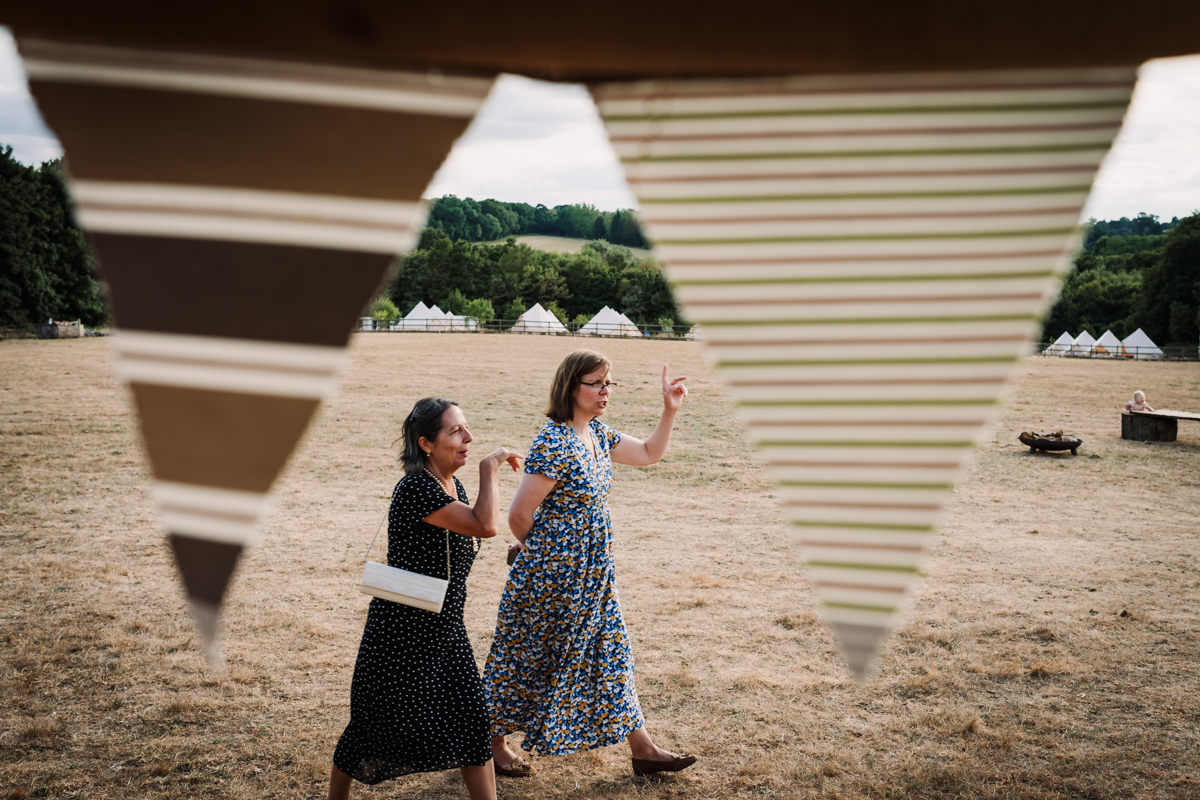 Wedding guests walk past festival bell tents towards the wedding breakfast marquee