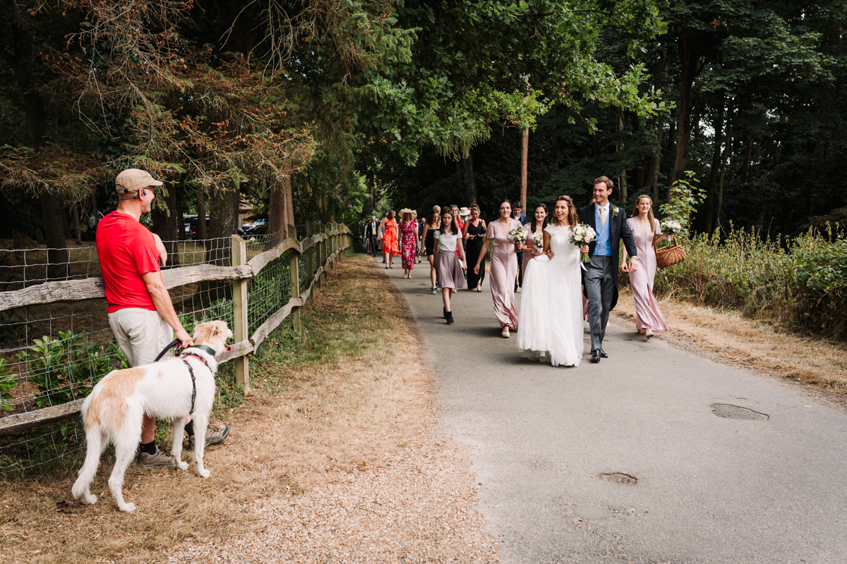 Bridal party and guests walk from the Hertfordshire church to the festival style wedding reception