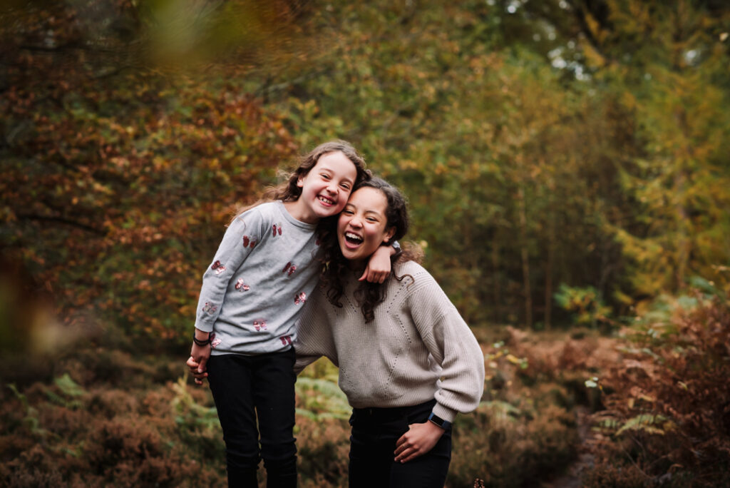 Sisters laugh in the Autumn woods in Hertfordshire